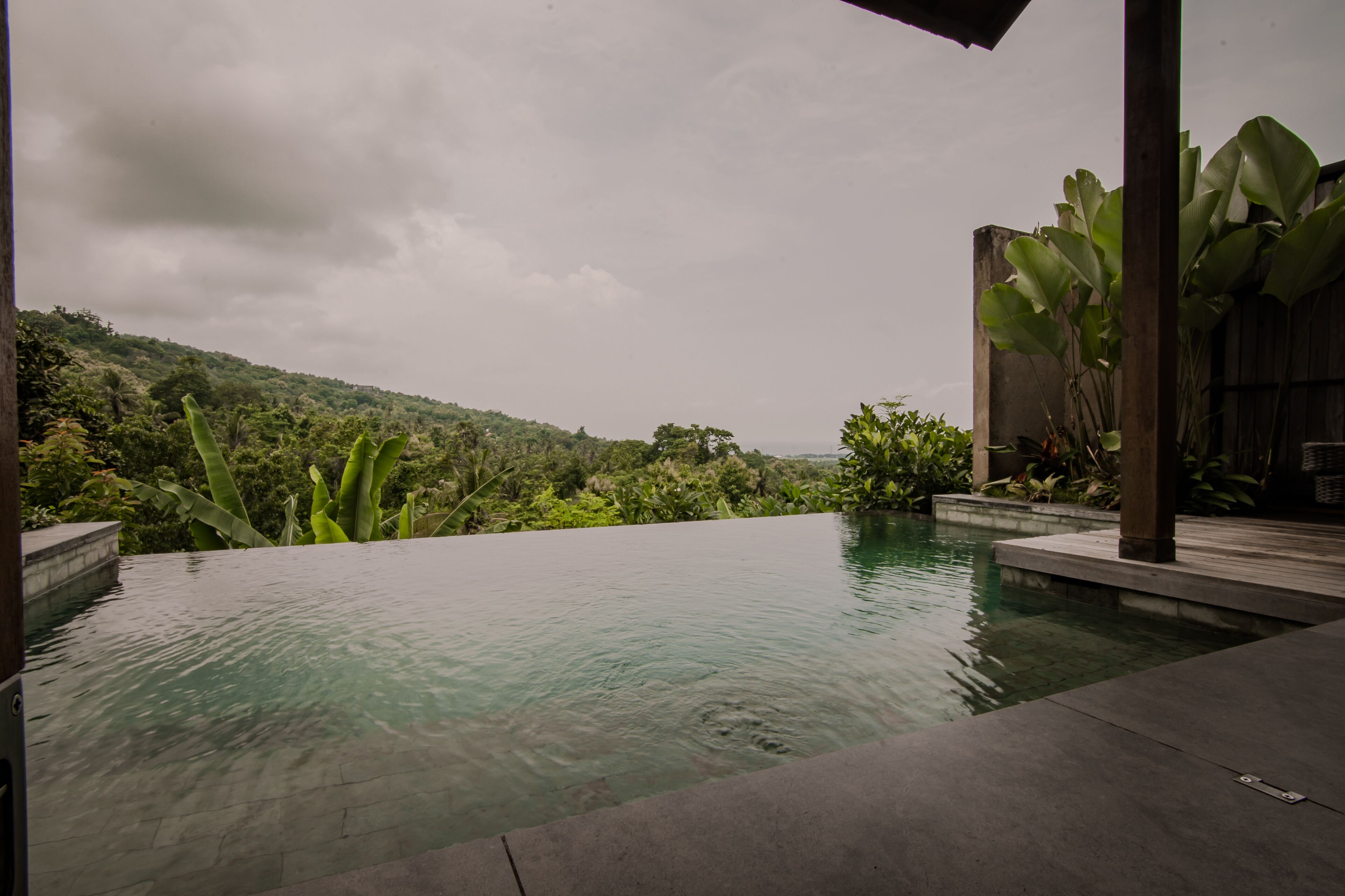 A serene infinity pool with a view of lush greenery and hills.