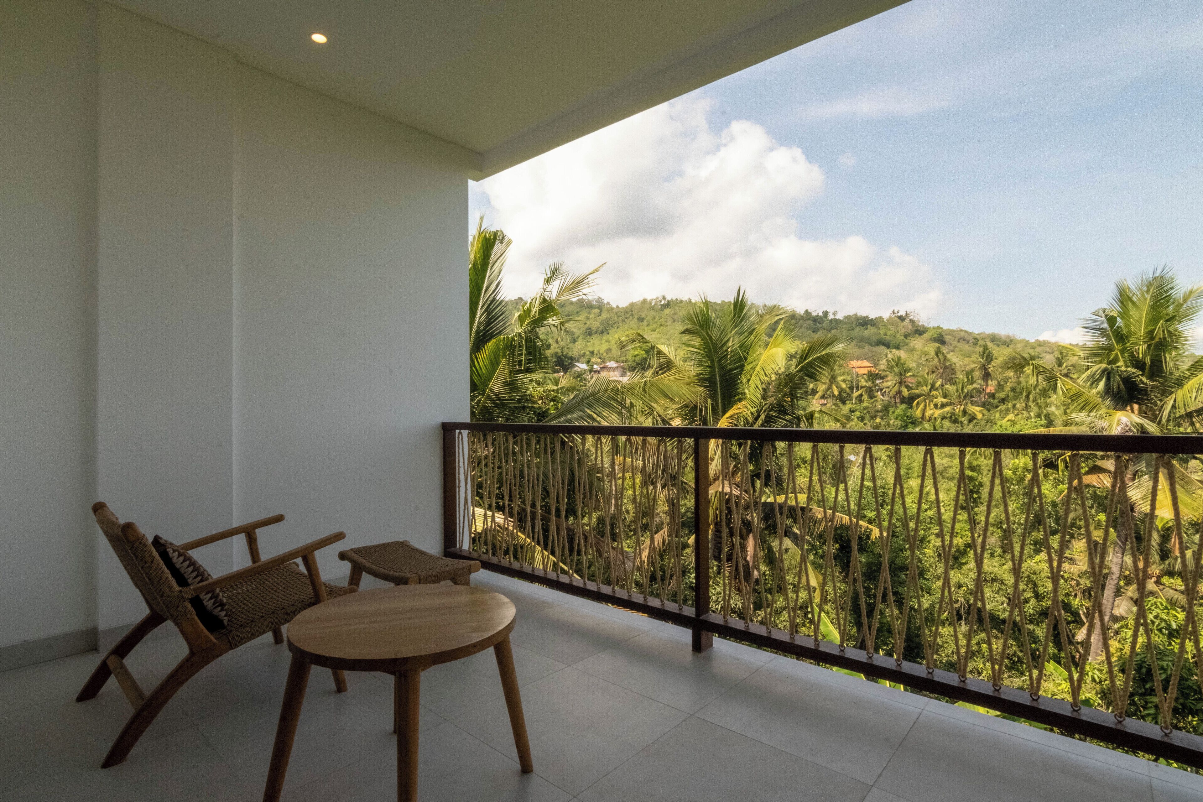 A balcony with a view of a lush green landscape and a clear sky.