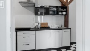A modern kitchen with white cabinets, black countertops, and a checkered floor. - MoHo Modern Hostel (Wroclaw)