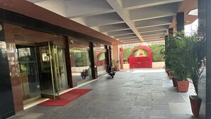 L’entrée d’un hôtel, avec un tapis rouge, des portes en verre et une moto garée à l’intérieur.