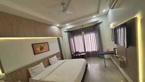 Une chambre d’hôtel moderne équipée d’un grand lit, d’un bureau, d’une télévision et d’un ventilateur de plafond.