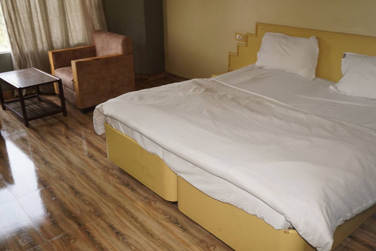 A room with a large bed, a chair, and a small table.