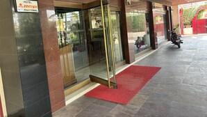 L’entrée de l’hôtel Maya International, avec son tapis rouge, ses portes en verre et une moto garée à l’extérieur.