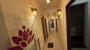 Un couloir d’hôtel, long et étroit, avec des appliques murales et un décor mural ornemental.