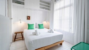 A bedroom with a wooden bed, white walls, and a window with white curtains. - The Handshake House by Shway (Antwerpen)