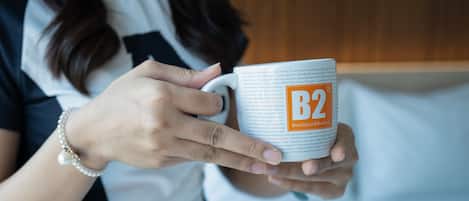 Uma pessoa segurando uma caneca com o texto 'B2 Boutique & Budget'.