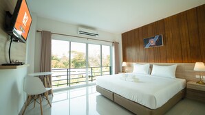 A hotel room with a large bed, a desk with a chair, a TV, and a window with a view of trees. - B2 Nakhon Sawan Boutique & Budget Hotel (Nakhon Sawan)