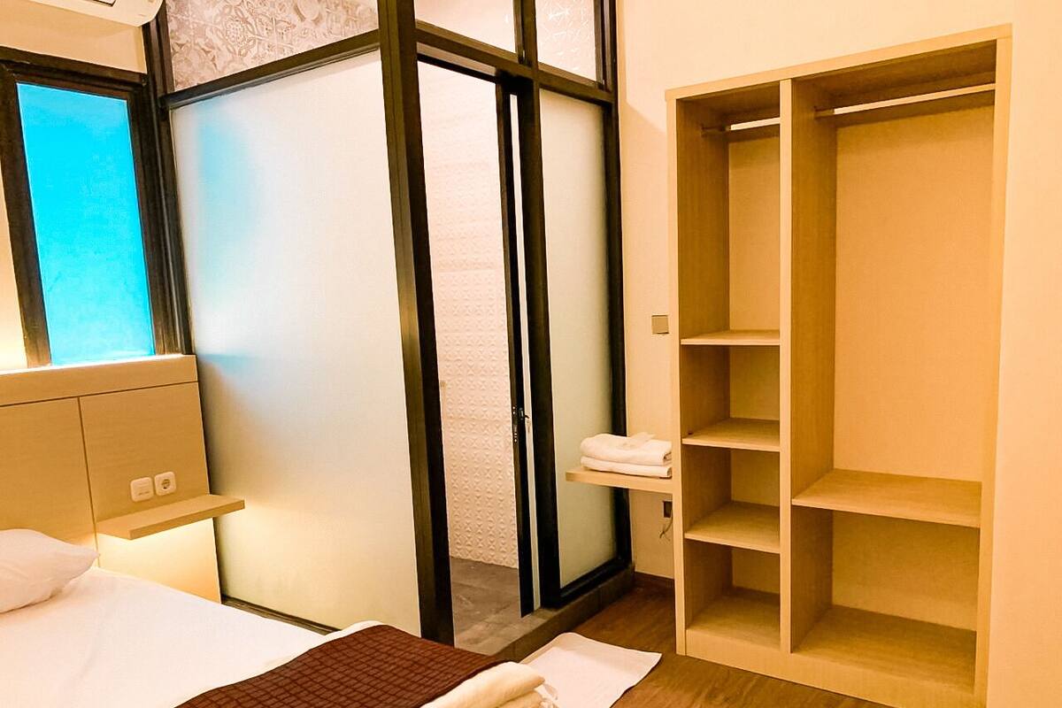 Ein Hotelzimmer mit Bett, Schrank, kleiner Ablagefläche und einer Schiebetür zu einem Badezimmer.