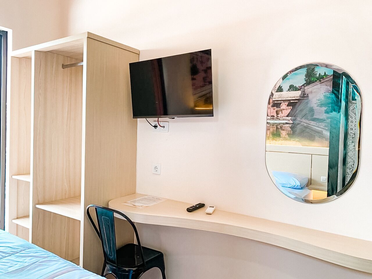 Une chambre à coucher avec un lit, un bureau avec une télévision, une chaise, un miroir et une armoire.