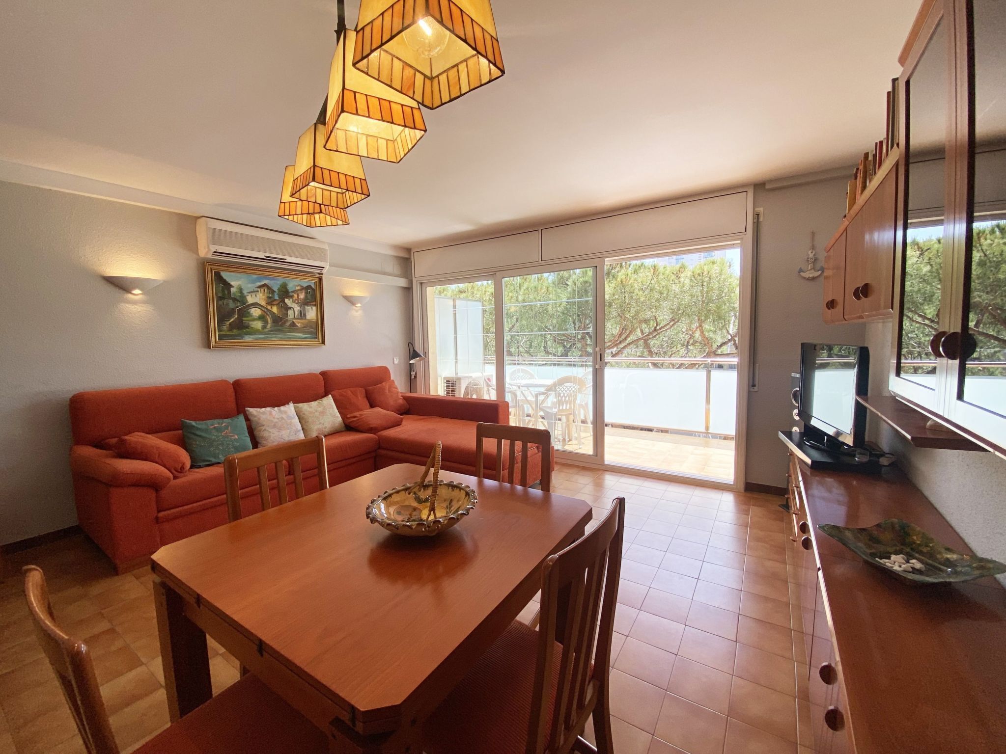 Uma sala de estar com uma mesa de jantar de madeira, um sofá vermelho e um quadro na parede.