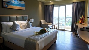 Habitación de hotel con una cama grande, un escritorio, una silla y un balcón con vistas.