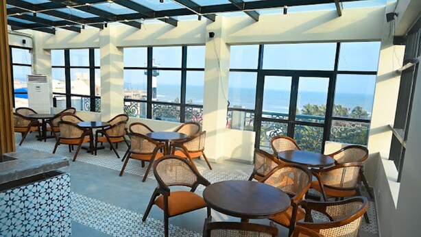 Una terraza en la azotea con mobiliario exterior, ventanas amplias y vistas a la ciudad.