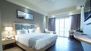 Una habitación de hotel moderna con una cama grande, lámparas de noche, un escritorio y una silla.