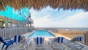 A pool area with lounge chairs and a wooden deck overlooking the ocean. - Bay Haven w/ Shared Boat Dock & Waterfront Pool | Big Trout by AvantStay (Corpus Christi)