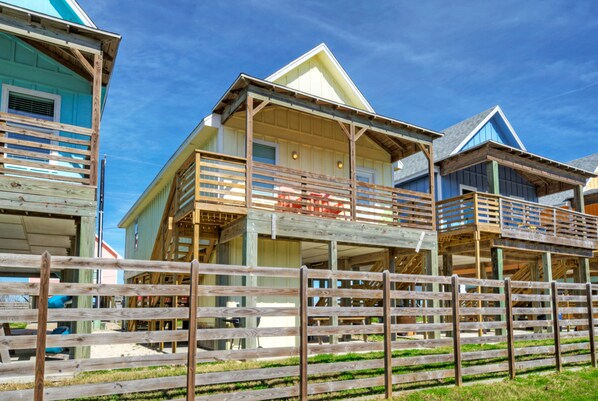 Une rangée de maisons en bois dotées de balcons, une clôture en bois au premier plan et un ciel bleu dégagé.