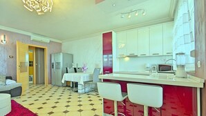Una cocina moderna con armarios blancos, una pared de acento roja y un comedor con sillas blancas.