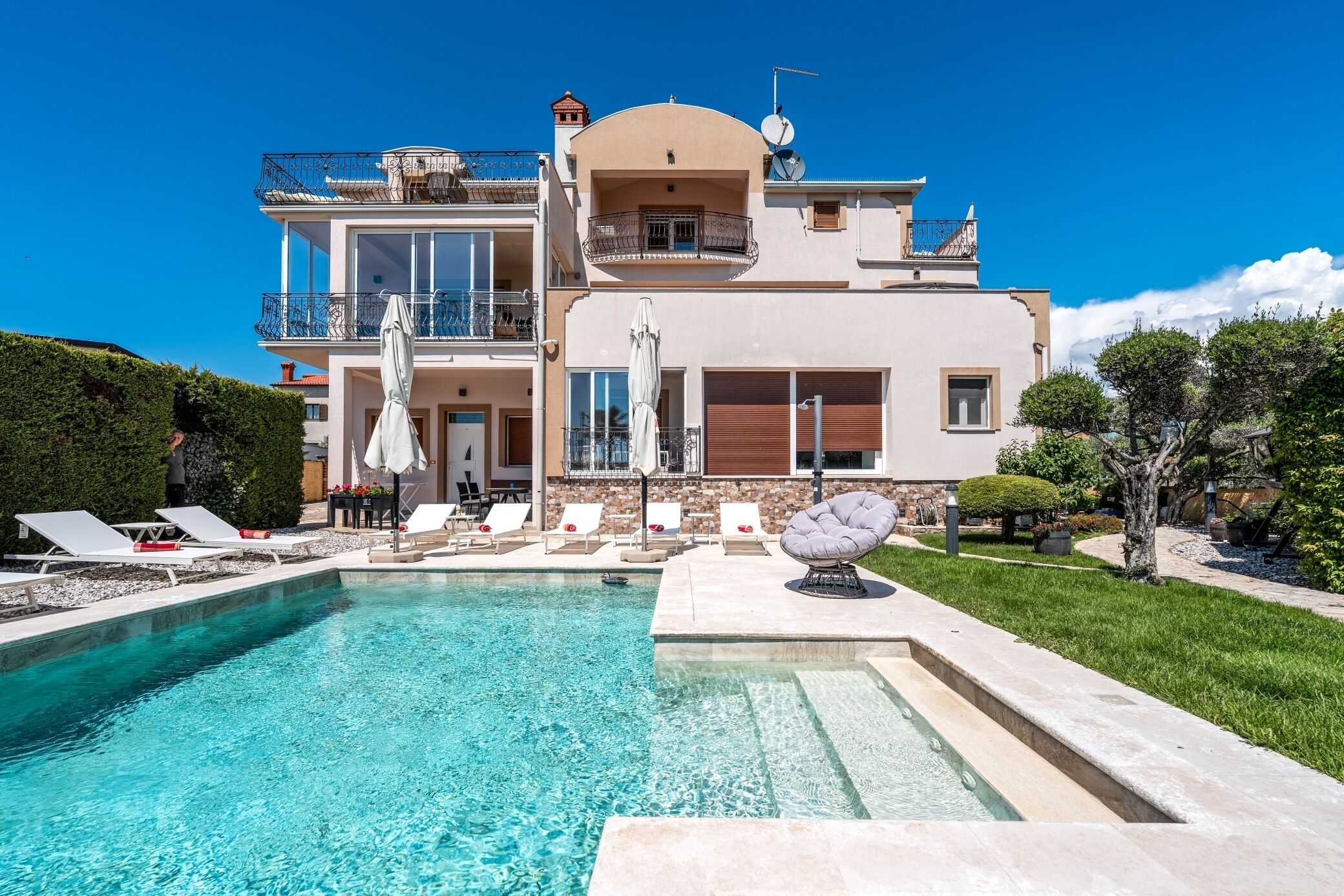 A large, two-story house with a swimming pool in the foreground.