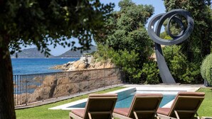 A pool area with lounge chairs, a metal sculpture, and a view of the sea. - VILLA DOLCE VITA- 8 bedrooms, sea view, swimming pool, (Ajaccio)