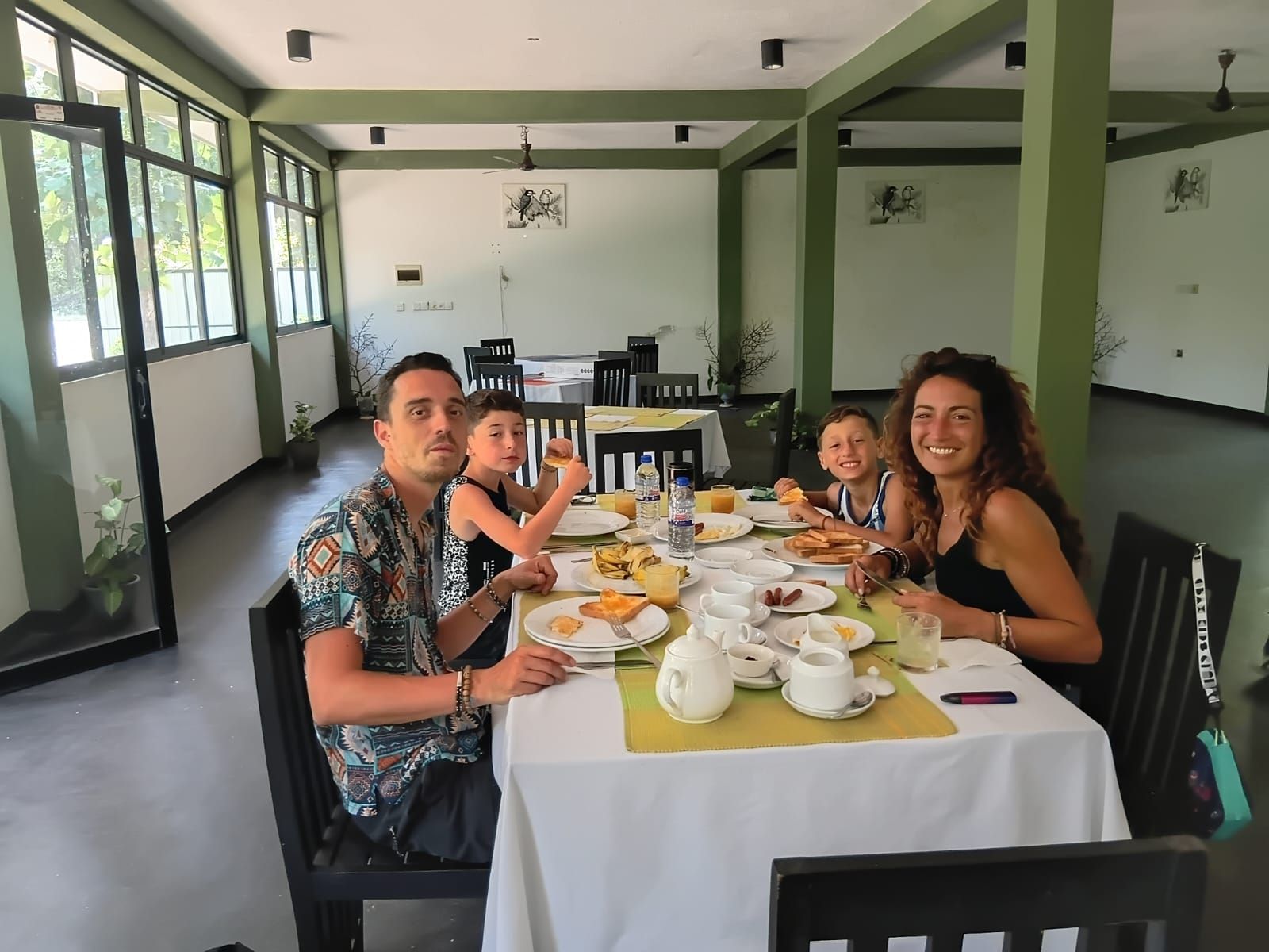 Comedor con una mesa dispuesta para cuatro personas, rodeada de sillas, y vistas al exterior a través de amplias ventanas.