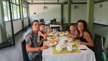Comedor con una mesa dispuesta para cuatro personas, rodeada de sillas, y vistas al exterior a través de amplias ventanas.