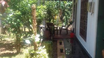 A covered outdoor area with a concrete path, potted plants, and a red carpet leading to a building entrance.