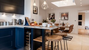 Een moderne keuken met een centraal eiland, barstoelen en een eethoek met een tafel en stoelen.