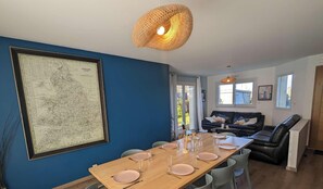 Un comedor con un mapa grande en la pared, una mesa de madera preparada para cuatro personas y un sofá de cuero negro al fondo.