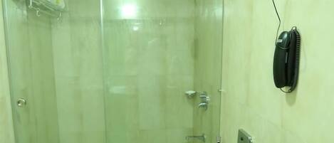 A bathroom with a glass-enclosed shower, a toilet, and a telephone mounted on the wall.