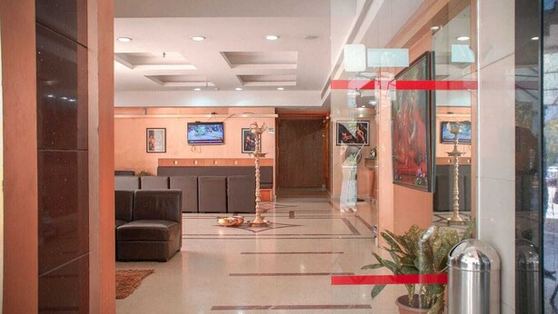 A hotel lobby with a reception desk, seating area, and a television screen. - PATTOM ROYAL HOTEL (Thiruvananthapuram)
