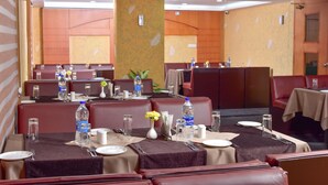 A restaurant with booths and tables, each set with plates, cutlery, and water bottles. - PATTOM ROYAL HOTEL (Thiruvananthapuram)