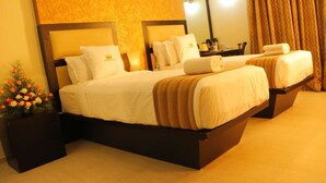 A hotel room with two beds, a large mirror, a nightstand, and a potted plant. - PATTOM ROYAL HOTEL (Thiruvananthapuram)
