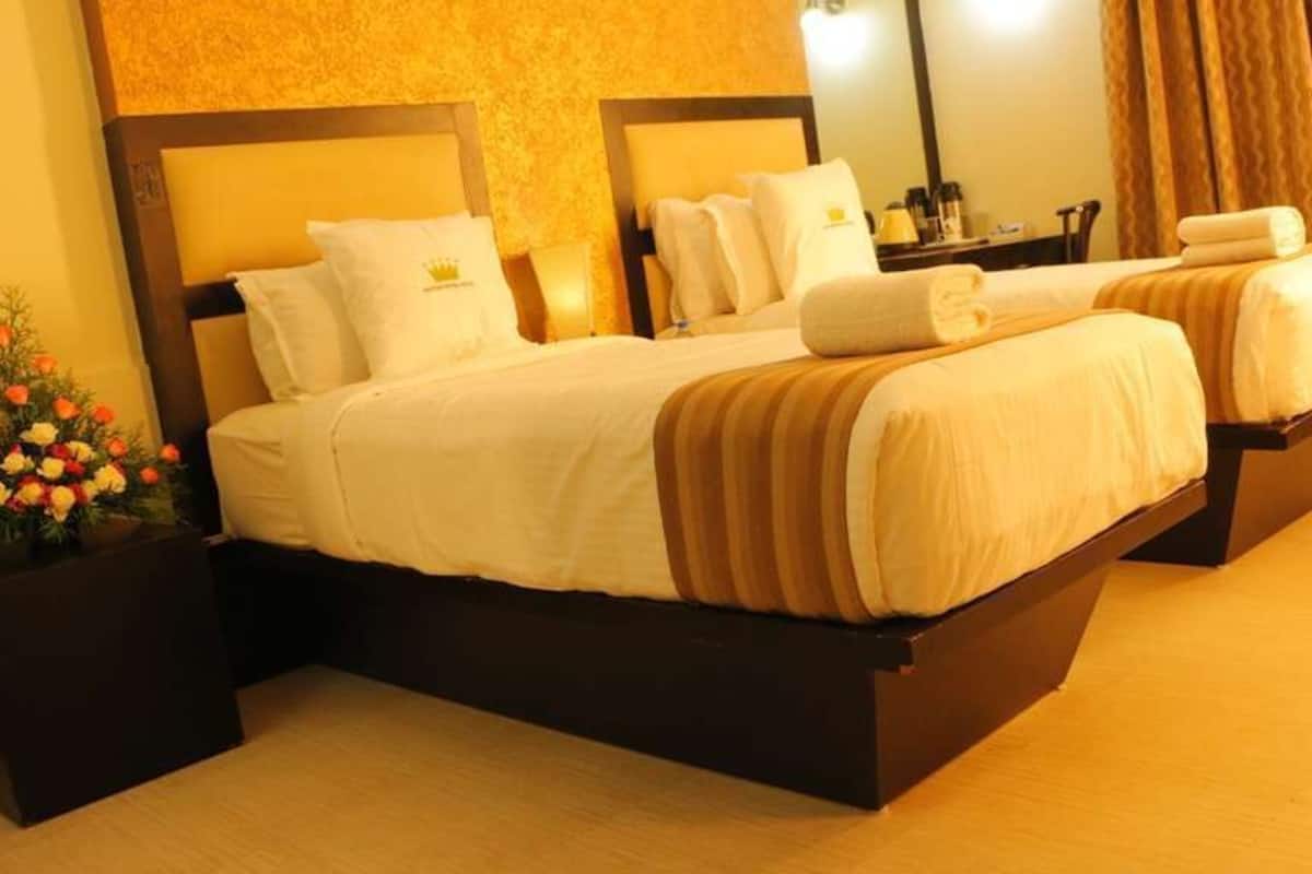 A hotel room with two beds, a large mirror, a nightstand, and a potted plant.