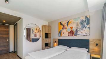 A modern hotel room with a large bed, a round mirror, and a colorful cityscape painting on the wall.