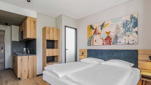 Un dormitorio moderno con una cama grande, un escritorio empotrado y un cuadro abstracto colorido en la pared.