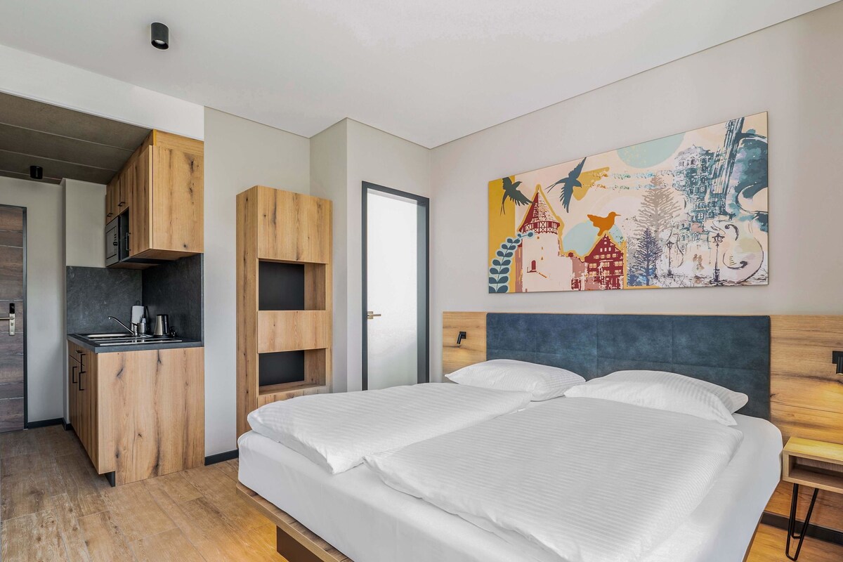 Une chambre moderne avec un grand lit, un bureau intégré et un tableau abstrait aux couleurs vives accroché au mur.