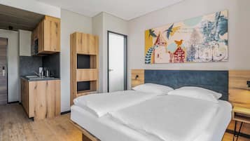 Ein modernes Schlafzimmer mit einem großen Bett, einem eingebauten Schreibtisch und einem farbenfrohen, abstrakten Gemälde an der Wand.