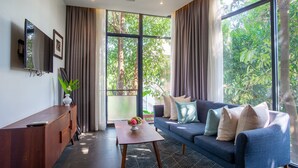 A modern living room with a sofa, a coffee table, and a TV mounted on the wall. - Maison Leab (Siem Reap)