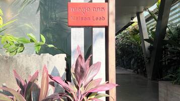A sign reading "Maison Leab" in front of a building with a modern architectural design, featuring a concrete structure and a glass entrance.