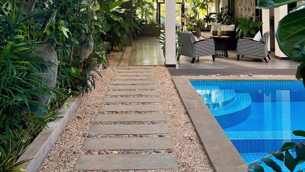 A covered outdoor area with a pool, surrounded by lush greenery and modern furniture. - Maison Leab (Siem Reap)