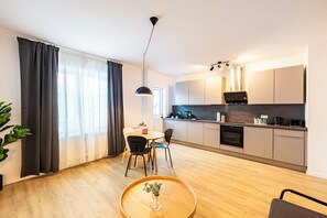 Una cocina moderna con zona de comedor, suelo de madera y un amplio ventanal con cortinas.