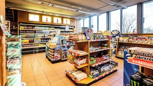 Uma loja de conveniência bem iluminada, com uma variedade de produtos nas prateleiras, incluindo lanches, bebidas e artigos de higiene pessoal.