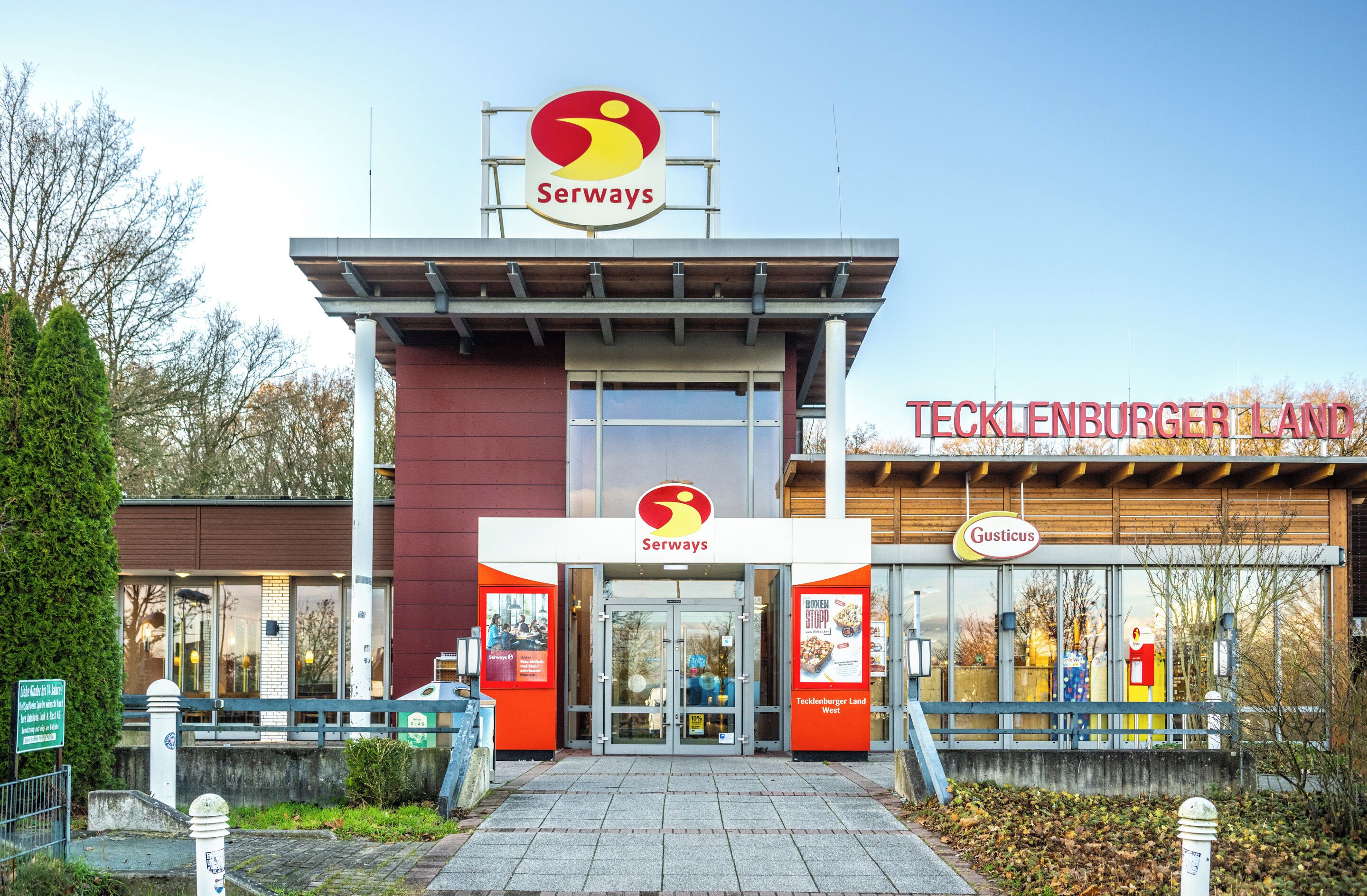 A Serways restaurant with a sign above the entrance and a nearby Tecklenburger Land establishment.