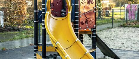 A playground with a yellow slide and climbing structures.