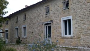 A stone building with multiple windows and a door, surrounded by gravel and some vegetation. - Château Pierre de Montignac (Civrac-en-Medoc)