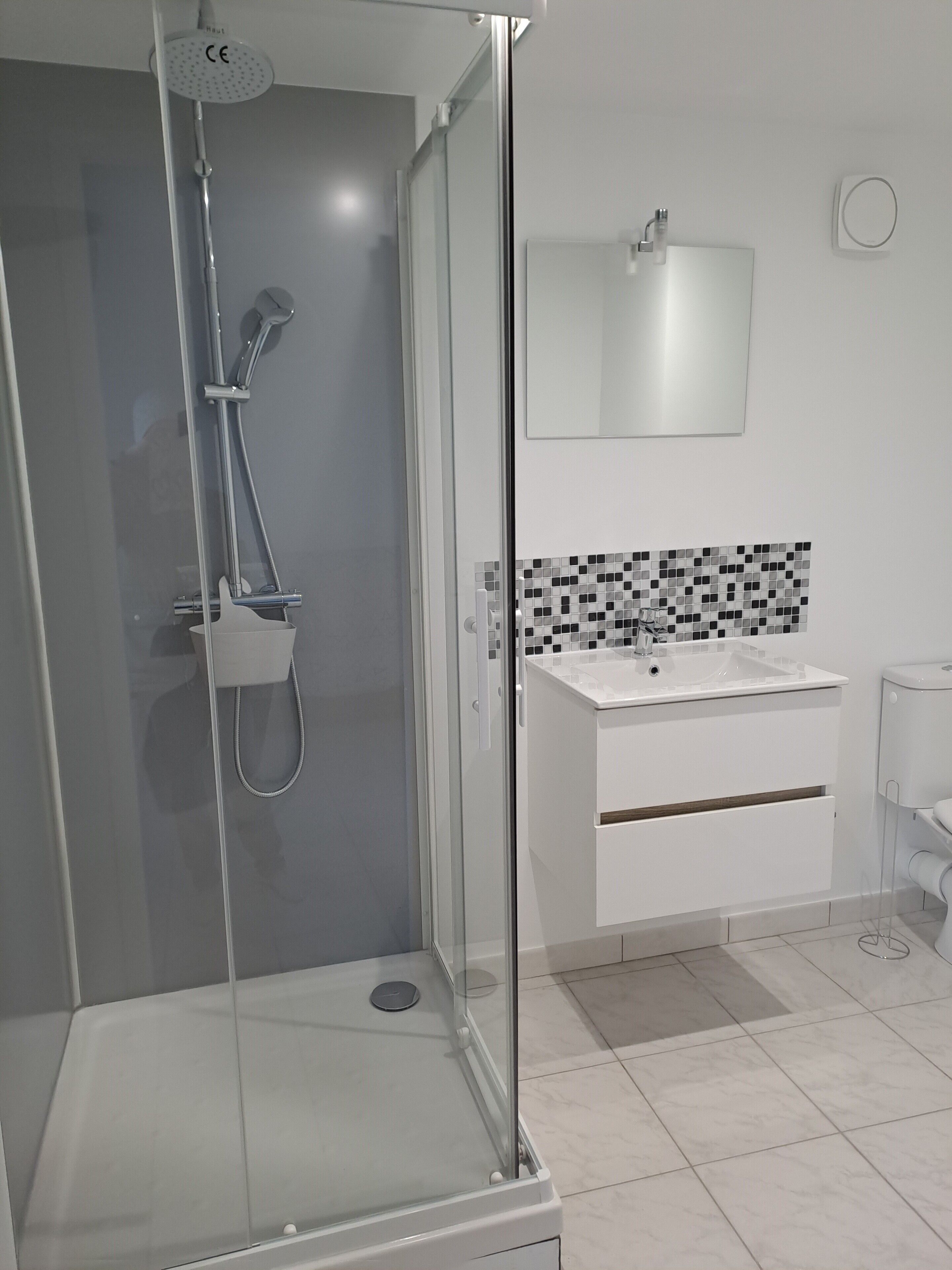 A modern bathroom with a glass-enclosed shower, a white sink, and a tiled backsplash.