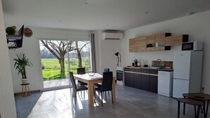 A modern kitchen with a dining area, large windows, and a view of a green landscape. - Château Pierre de Montignac (Civrac-en-Medoc)