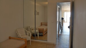 A room with a bed, a chair, and a sliding glass door leading to another room.