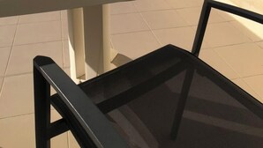 A table with a cup on it, a chair, and a view of the sea.