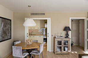 Uma área de refeições com mesa e cadeiras de madeira, uma luminária pendente e um armário com portas de vidro.