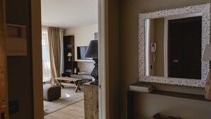 A room with a television, a lamp, a mirror, and a wooden bench.